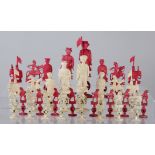 A Chinese export carved ivory figural Chess Set, late 19th Century, stained red and natural, the