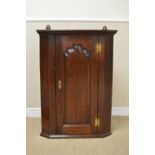 An 18th Century oak Hanging Corner Cupboard with shaped fielded panel door enclosing shelves, 3ft