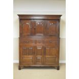 An 18th Century oak Court Cupboard with three cupid's bow panelled doors fronted by turned finals,