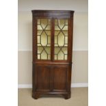 A Georgian oak Double Corner Cabinet with cross-banded frieze above a pair of astragal glazed doors,