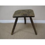 An antique oak Potters Stool with solid seat on three primitive chamfered splay legs, 14 x 9in