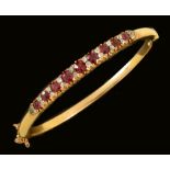 A Ruby and Diamond hinged Bangle, the front pavé-set graduated cushion-cut rubies interspersed