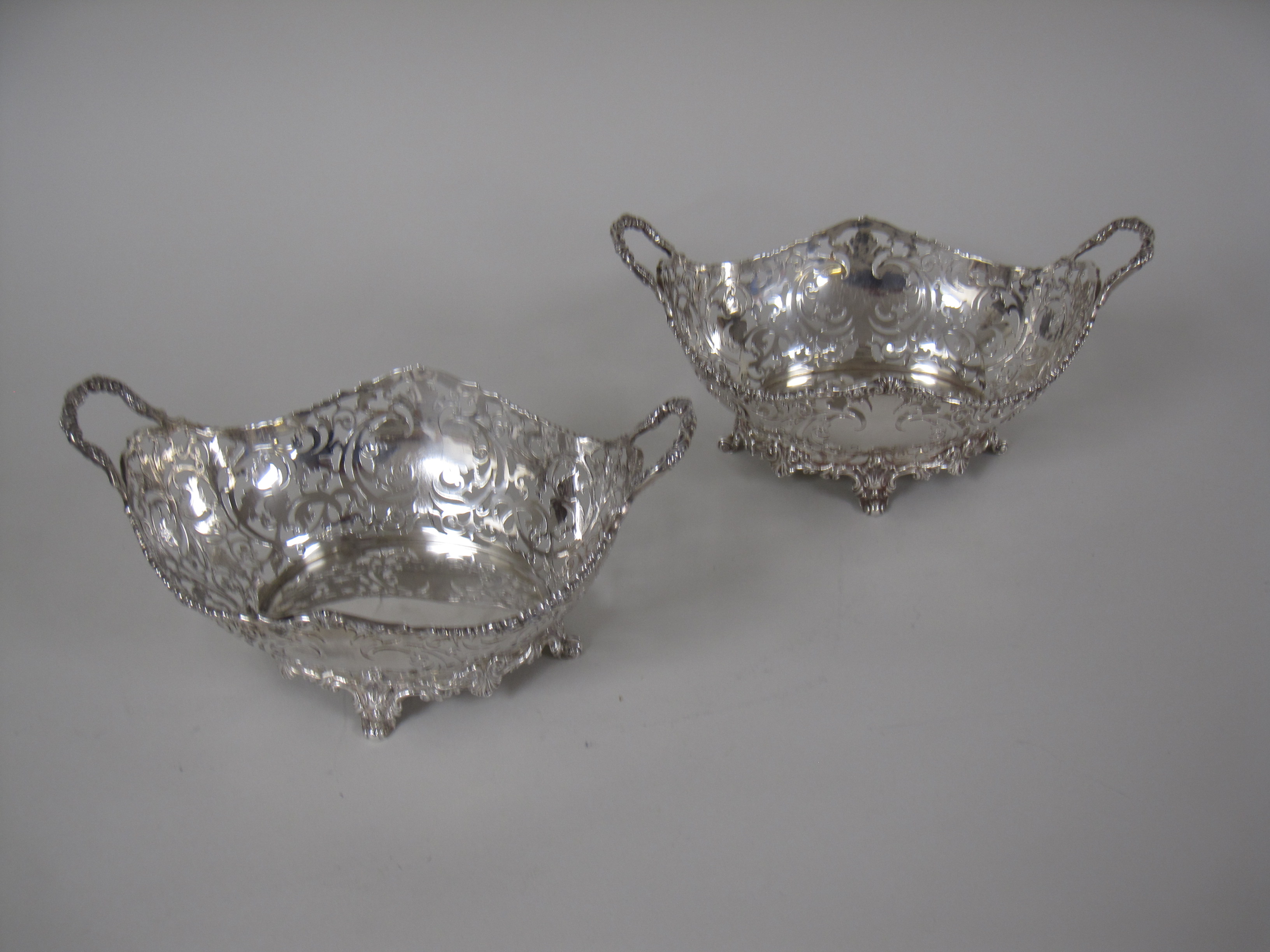 A pair of George V silver pierced oval two handled Baskets on scroll feet, London 1925, 10 x 6in,