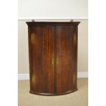 A late 18th Century oak bow front Corner Cupboard with pair of doors having brass H hinges enclosing