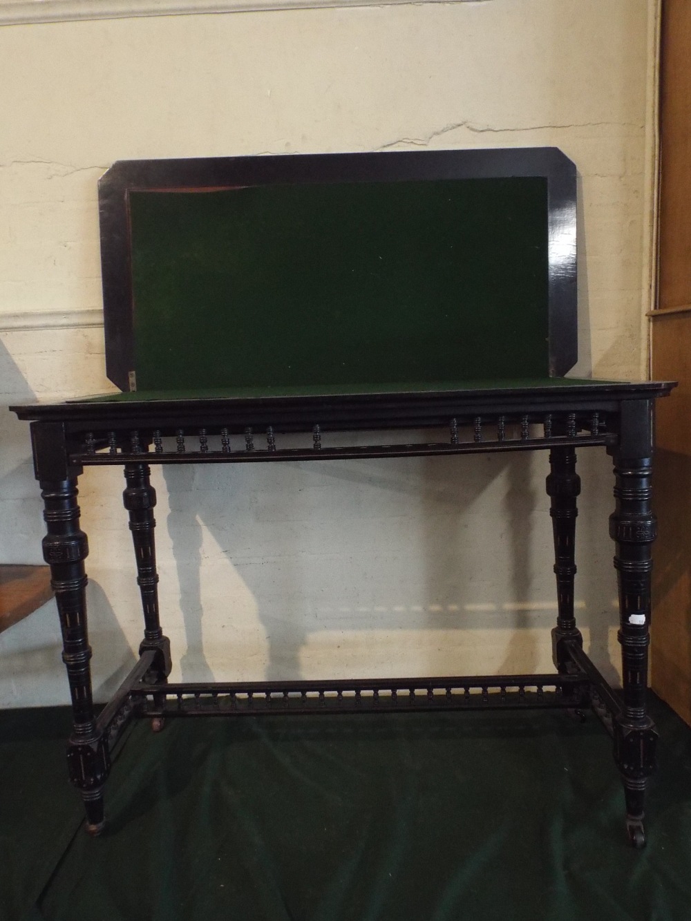 An Aesthetic Movement Lift and Twist Ebonised Games Table on Turned Supports, Some Missing Spindles,