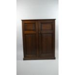 An Edwardian Oak Shelved Side Cabinet with Panelled Doors and Plinth Base. 93x40x114cms