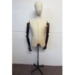 A Fabric Mannequin Male Torso with articulated wooden arms, the mannequin on metal support with