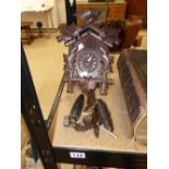 A BLACK FOREST CARVED WOODEN CUCKOO CLOCK WITH HANGING WEIGHTS (CLOCK IS 28 CM TALL)