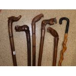 SIX CARVED WALKING STICKS IN EMBOSSED BRASS STICK STAND