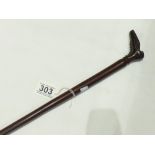 AN UNUSUAL MAHOGANY WALKING STICK, THE HANDLE CARVED IN THE SHAPE ODF A BOOT. 90CM IN LENGTH
