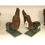 A PAIR OF BRONZE HAND BOOKENDS ON WOODEN BASES