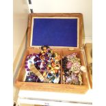 A CARVED WOODEN JEWELLERY BOX WITH COSTUME JEWELLERY - MAINLY BROOCHES WITH NECKLACES AND BRACELETS