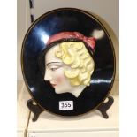 AN ART DECO 1930s GERMAN CERAMIC WALL MASK ON WOODEN BACK.