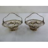 A pair of George III silver bonbon baskets, pierced circular with swing handles on raised circular