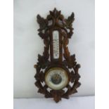 A Black Forest style Victorian barometer with circular dial and carved foliate mount