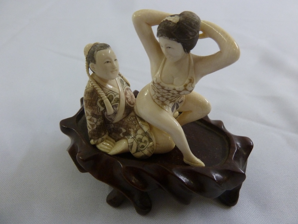 Japanese late 19th century erotic two part Netsuke on hardwood stand, 9cm (h) incl. stand