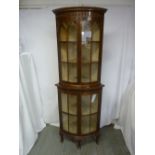 A Victorian mahogany double door glazed breakfront bow fronted corner cabinet