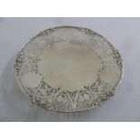 A silver pierced circular cake stand on raised circular base with applied vine leaf border,