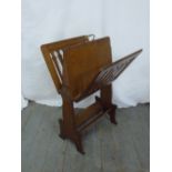 An arts and crafts oak magazine rack of rectangular form with pierced sides on bracket supports