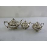 A Persian three piece white metal teaset heavily chased with flowers, scrolls and vegetation