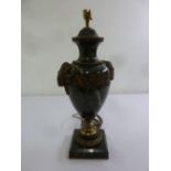A green vase form lamp base with applied rams heads and floral swags on square marble base