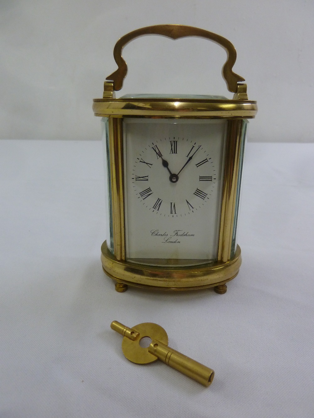 Charles Frodsham of London brass carriage clock, shaped oval, white enamel dial with Roman