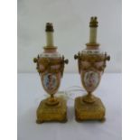 A pair of French porcelain and ormolu table lamps, decorated with putti, the square bases on