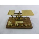 A set of brass postal scales with brass weights on rectangular wooden base