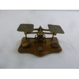 A set of brass postal scales with weights on shaped rectangular oak base
