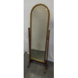 A mahogany cheval mirror with faceted arched top on four scroll supports