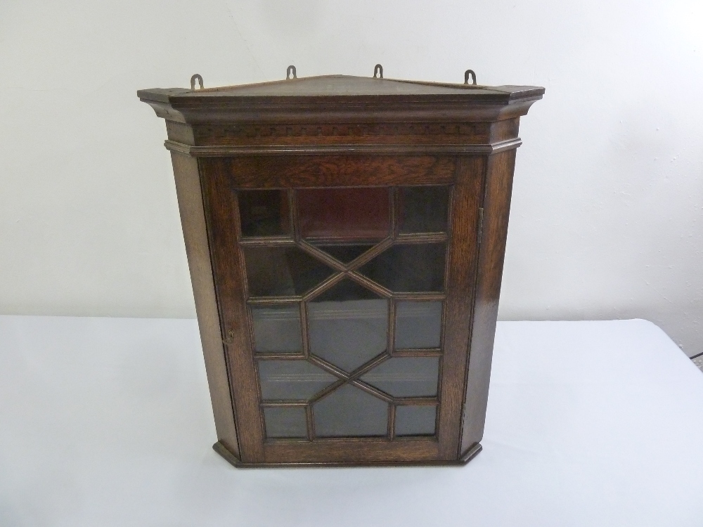 A Victorian oak wall mounted corner cabinet with hinged glazed door