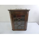 A Victorian oak wall mounted corner cabinet with hinged glazed door