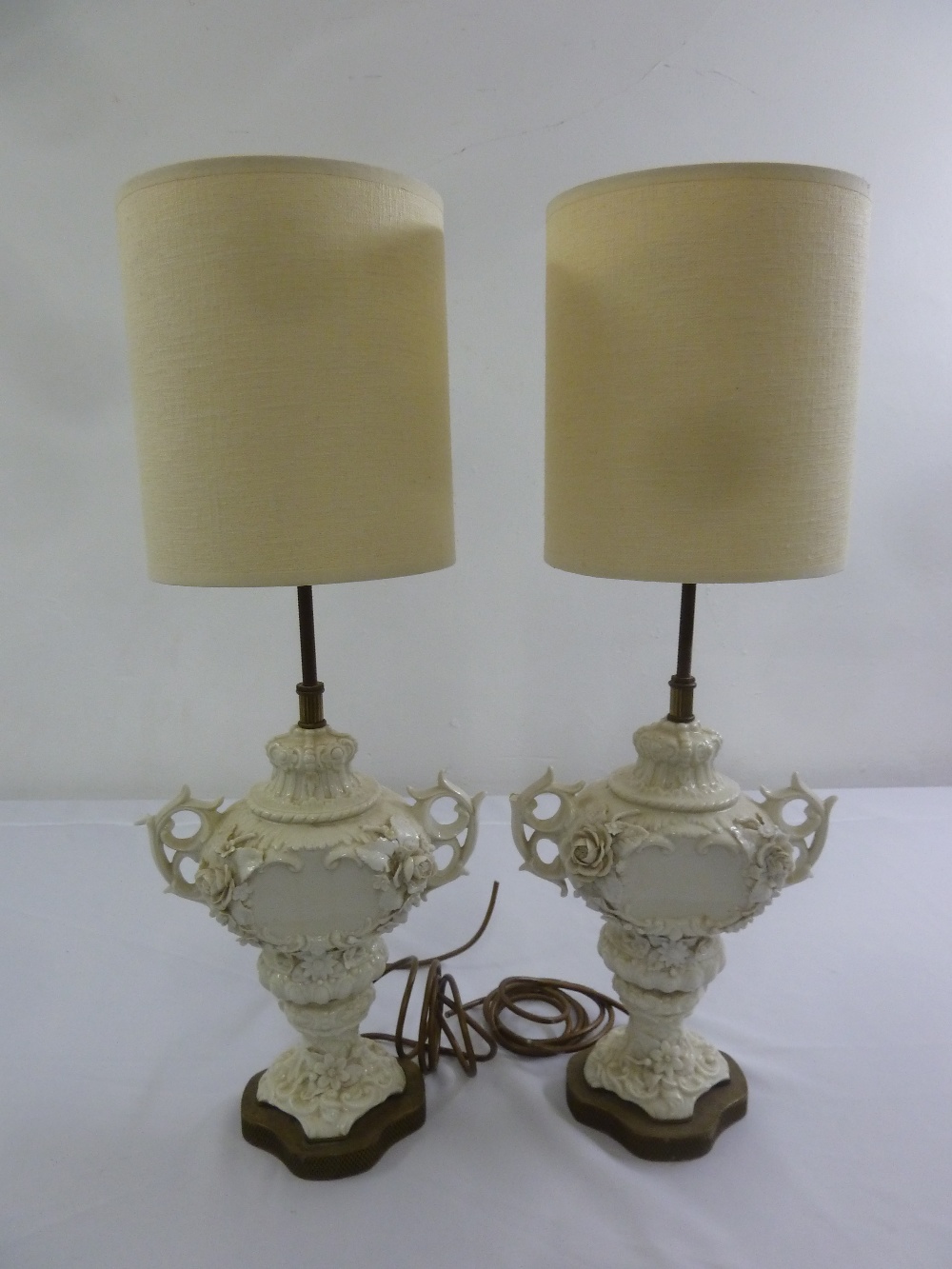 A pair of Blanc de Chine table lamps in the form of vases with scroll pierced side handles to