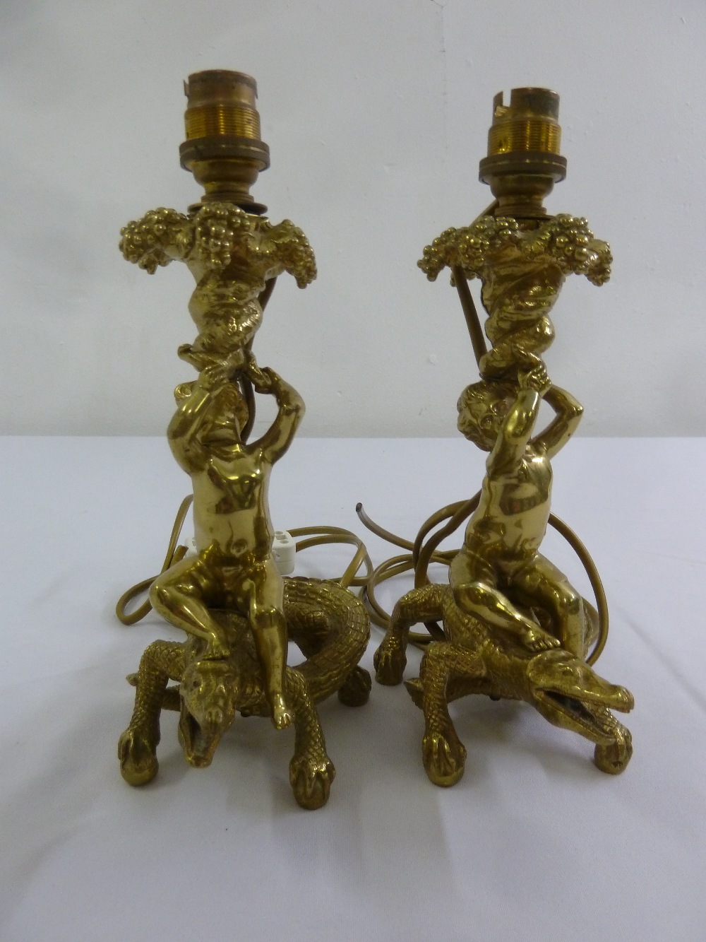 A pair of gilded metal table lamps in the form putti and lizards