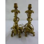 A pair of gilded metal table lamps in the form putti and lizards