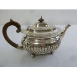 A late Victorian silver teapot, oval part fluted on four ball feet, London 1894