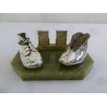 An Aspreys silver mounted photograph frame with applied miniature childs shoes on hexagonal onyx