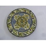 A Delft style wall plate decorated with stylised flowers and leaves signed AD to verso