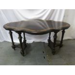 A Victorian shaped oval ebonised table on six turned legs