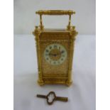 A gilded metal carriage clock decorated with filigree sides, enamel dial with Arabic numerals, to