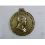A silver plated circular metal wall plaque with a gentlemans head in profile