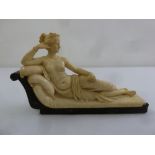 A composition figurine of a recumbent classical lady on a day bed mounted on a wooden base