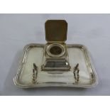 A silver Art Deco style inkstand, rounded rectangular with hinged cover to the well on four ball