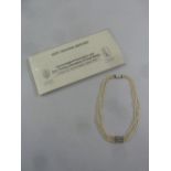 A three row graduated natural pearl necklace with white metal clasp and colourless stone spacer,