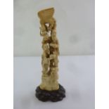 An Oriental 19th century carved ivory figural group on carved hardwood stand