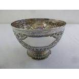 A late Victorian silver punch bowl decorated with flowers and stylised leaves on raised circular