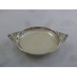 A silver circular sweetmeat dish with pierced sides and two scroll pierced side handles, London
