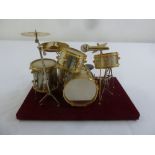 A scale model of a drum kit mounted on a rectangular plinth