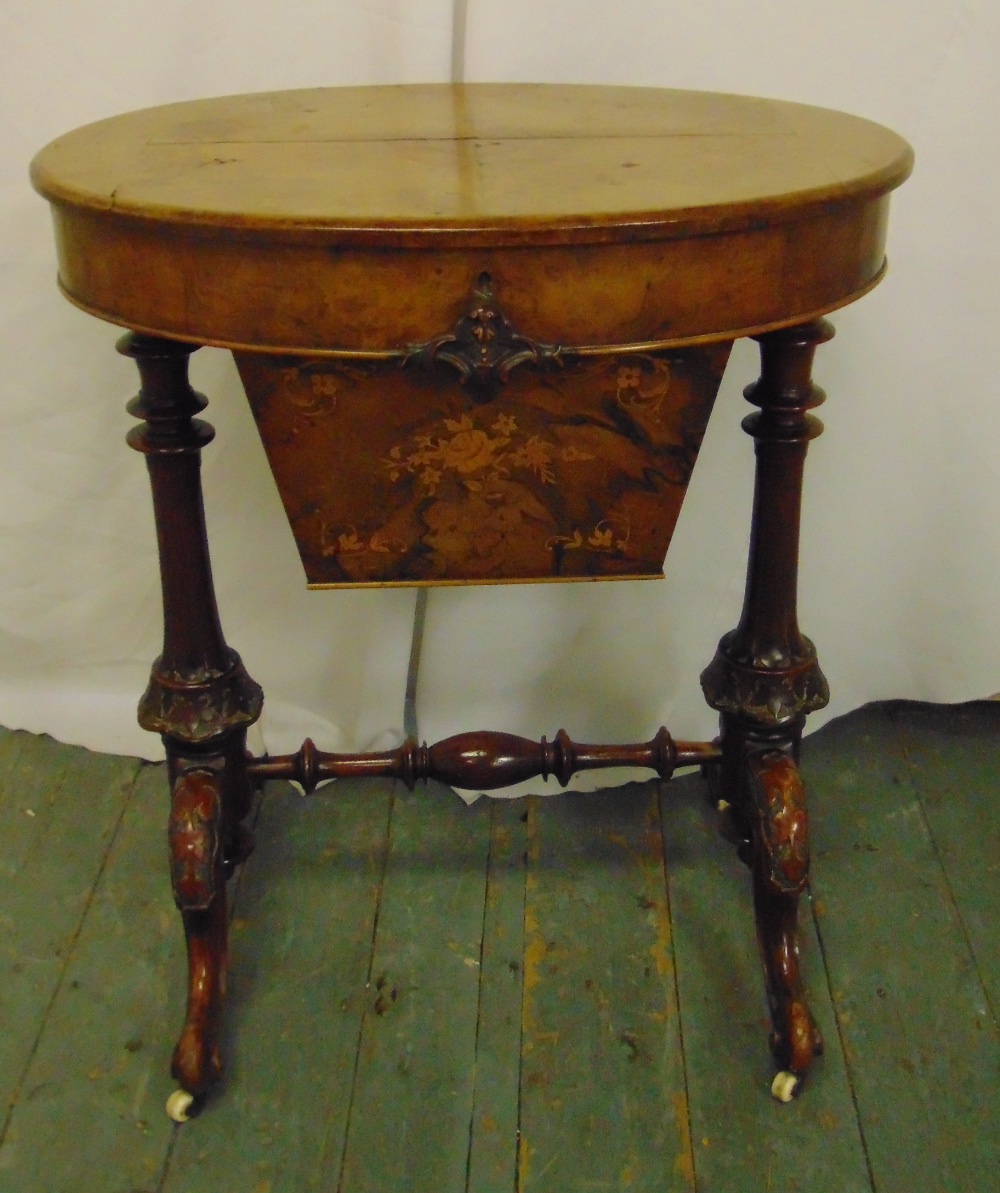 A Victorian oval sewing table on carved scrolling legs