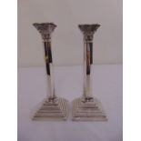 A pair of Corinthian column silver table candlesticks on stepped square bases with beaded borders,